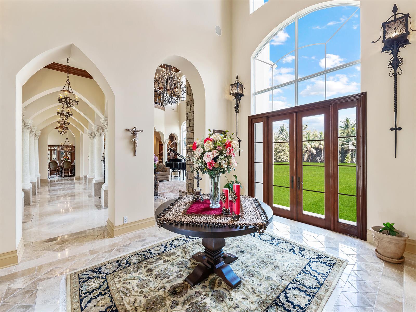 A grand foyer features arched walkways, a central pedestal table, and large glass entry doors — 8800 NW 68th Court, Parkland FL 33067, PARKLAND, FL