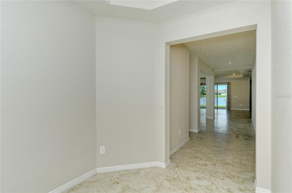 A view from a foyer looking through a hallway toward a room with water views — 16921 HARVEST MOON WAY, BRADENTON, FL