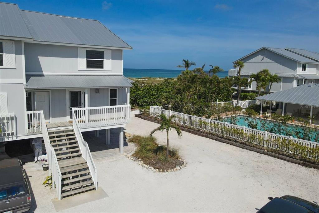 An elevated coastal house with a wooden staircase, a sandy yard, and a swimming pool — 420 GULF BOULEVARD UNIT 13, BOCA GRANDE, FL