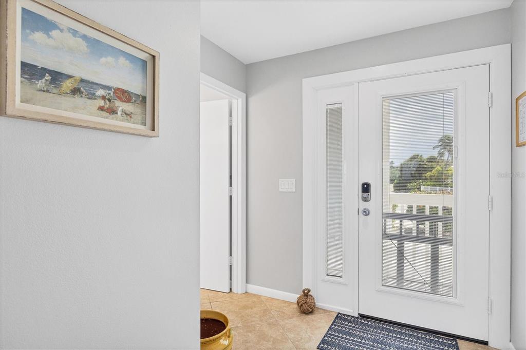 An entryway features a white front door with glass panels, tile flooring, and wall art — 420 GULF BOULEVARD UNIT 13, BOCA GRANDE, FL