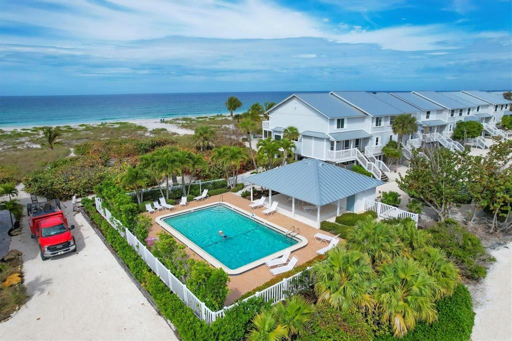 An aerial view shows a swimming pool, a covered patio, and a building near the beach — 420 GULF BOULEVARD UNIT 13, BOCA GRANDE, FL