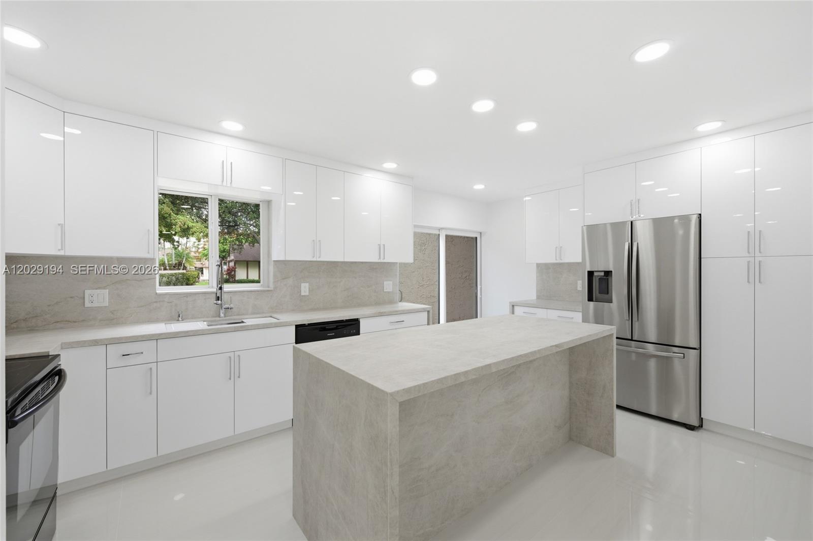 A modern kitchen features white cabinets, a stone-topped island, and stainless steel appliances — 22384 Thousand Pines Ln, Boca Raton FL 33428, BOCA RATON, FL