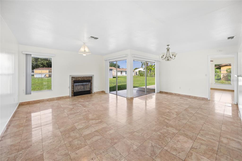A living room with tile flooring, a fireplace, and sliding glass doors leading to a yard — 714 TOURNAMENT LANE, KISSIMMEE, FL