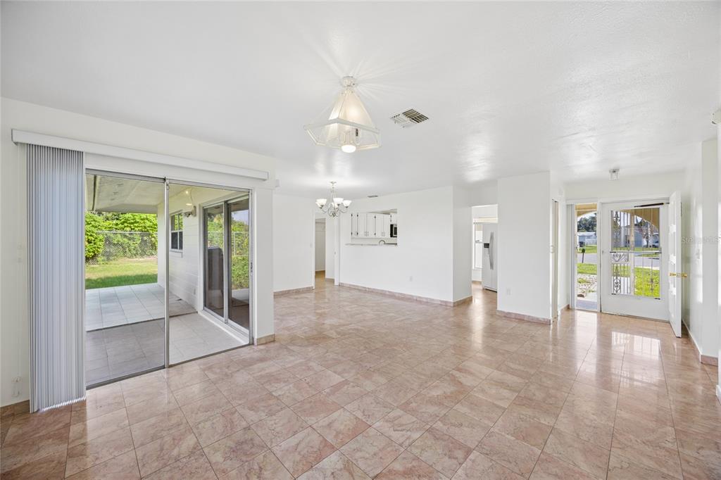 A bright living area features tile flooring, a sliding glass door, and an open entryway — 714 TOURNAMENT LANE, KISSIMMEE, FL