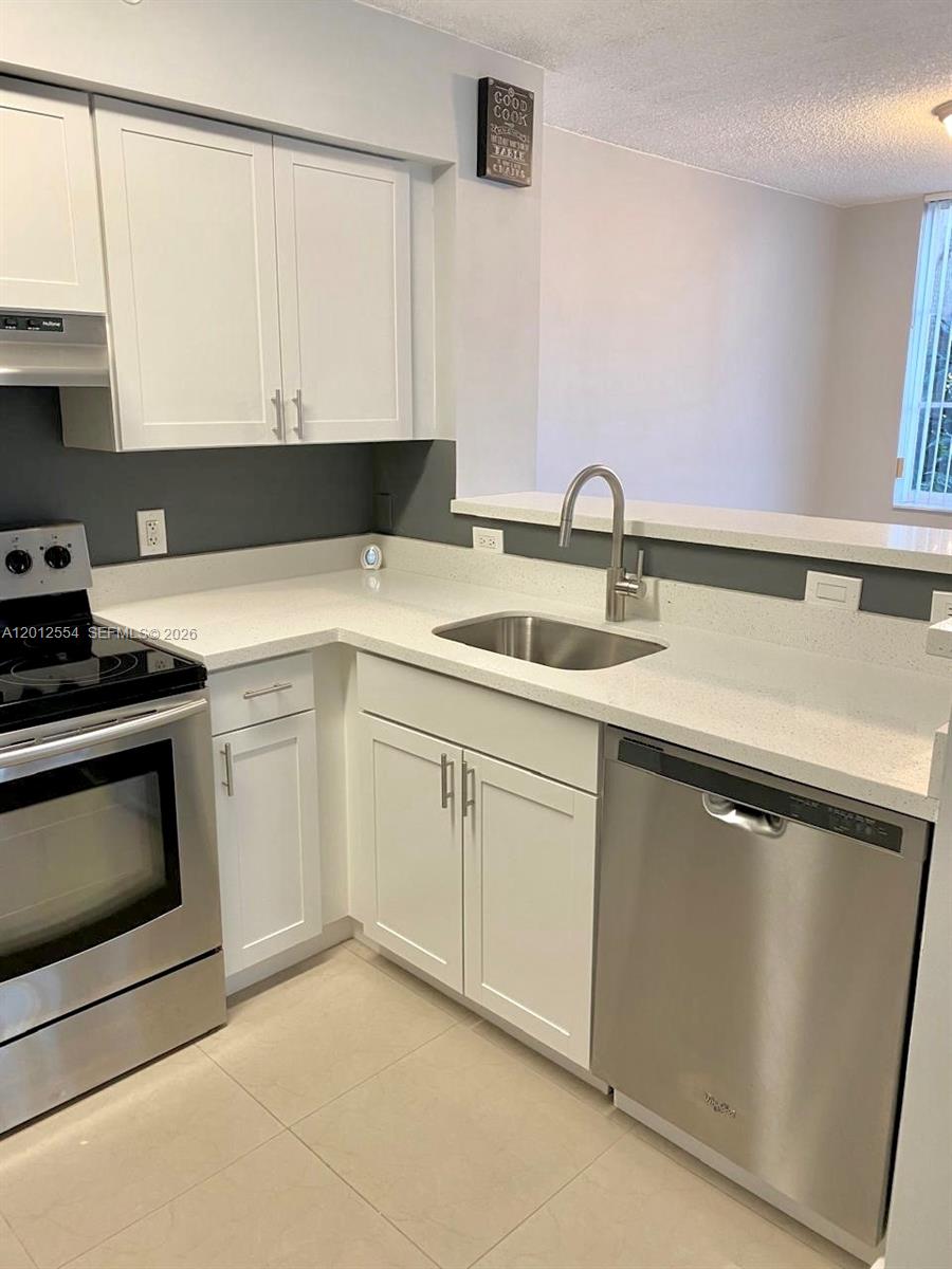 A kitchen features white cabinets, stainless steel appliances, and a light-colored countertop — 12118 Saint Andrews Pl # 107, Miramar FL 33025, MIRAMAR, FL