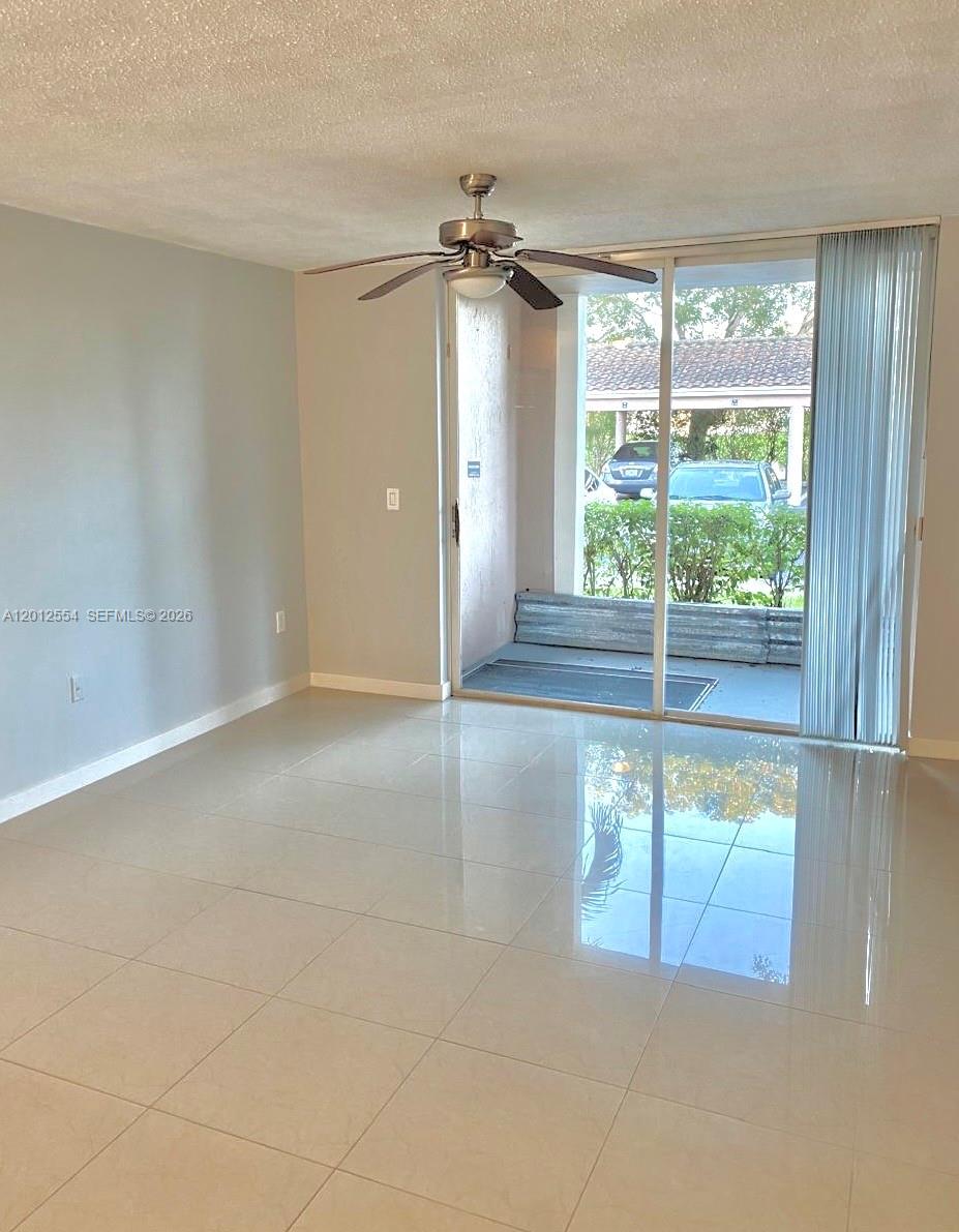 A living room with light-colored tile floors features a ceiling fan and sliding glass doors — 12118 Saint Andrews Pl # 107, Miramar FL 33025, MIRAMAR, FL