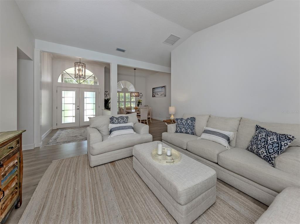 A living room features light-colored furniture, a large area rug, and an open dining area — 1428 GLENEAGLES DRIVE, VENICE, FL
