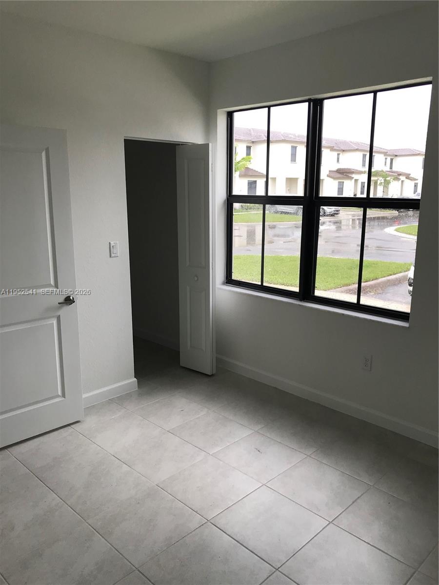 A room with light-colored tile flooring, a window, and an open closet door — 12989 SW 233rd Ter # 12989, Miami FL 33032, MIAMI, FL
