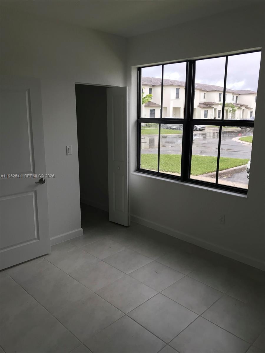 A room with light-colored tile flooring, a closet, and a large window overlooking a street — 12989 SW 233rd Ter # 12989, Miami FL 33032, MIAMI, FL