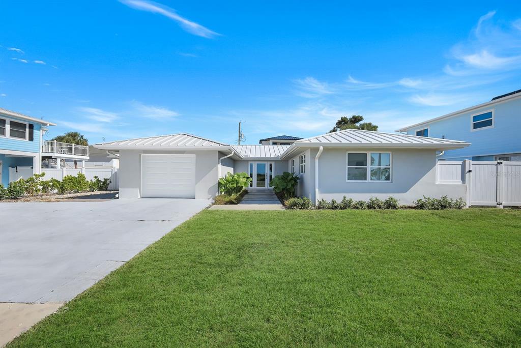 A single-story house with a white exterior, metal roof, and attached garage under a blue sky — 7987 ESTERO BOULEVARD, FORT MYERS BEACH, FL
