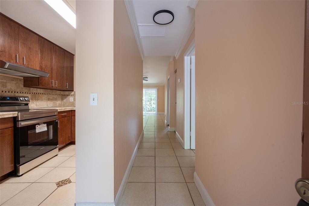 A hallway with tile flooring leads from a kitchen toward a bright living area — 3409 NW 52ND TERRACE, GAINESVILLE, FL
