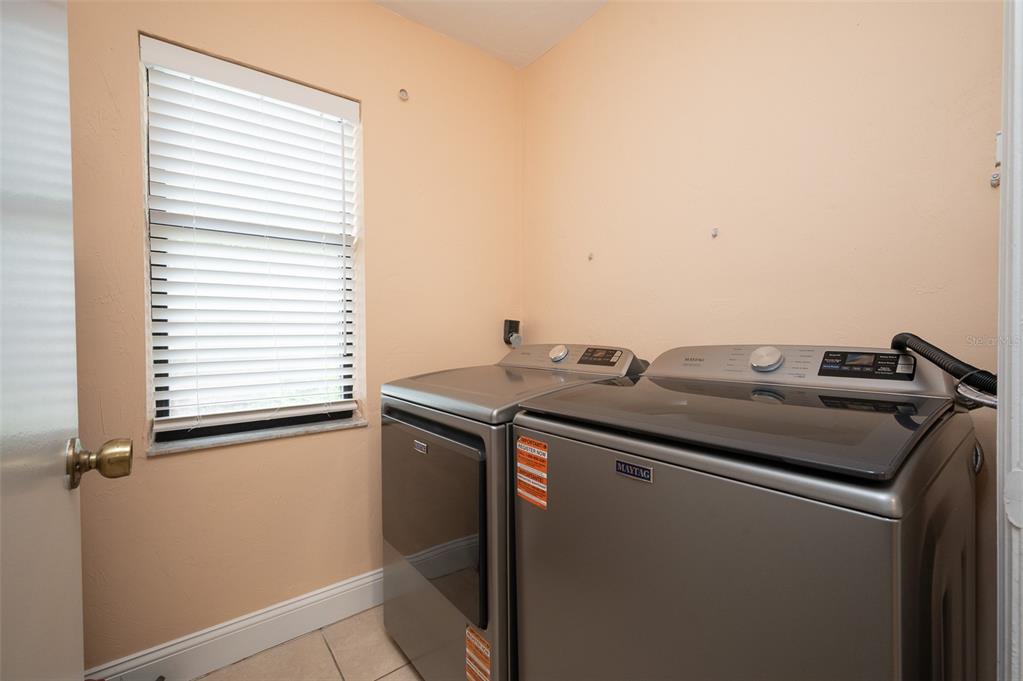 A laundry room features a stainless steel washer and dryer set against a peach wall — 3409 NW 52ND TERRACE, GAINESVILLE, FL
