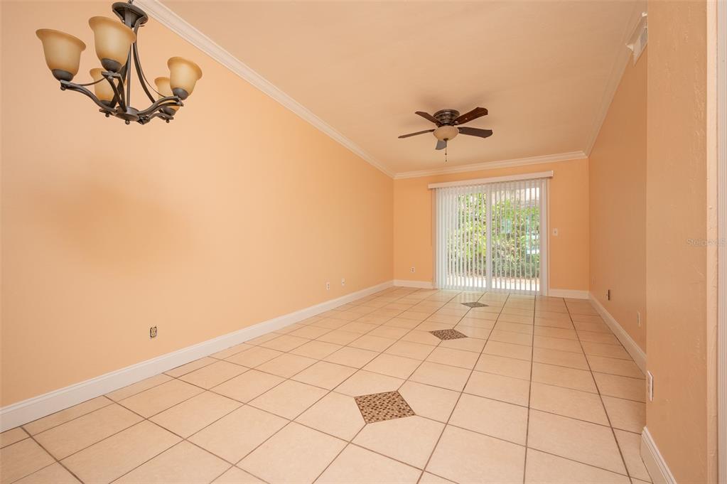An empty room with peach walls, tile flooring, a ceiling fan, and sliding glass doors — 3409 NW 52ND TERRACE, GAINESVILLE, FL