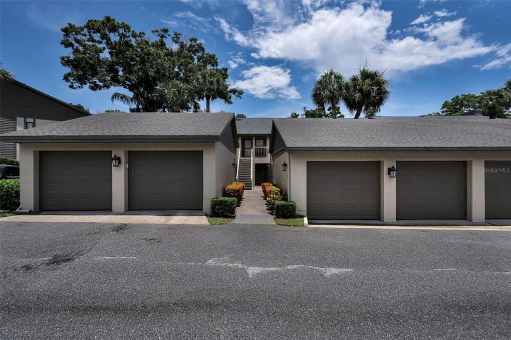 A view of a residential building exterior featuring four garage doors and a central walkway — 3165 LANDMARK DRIVE UNIT 711, CLEARWATER, FL