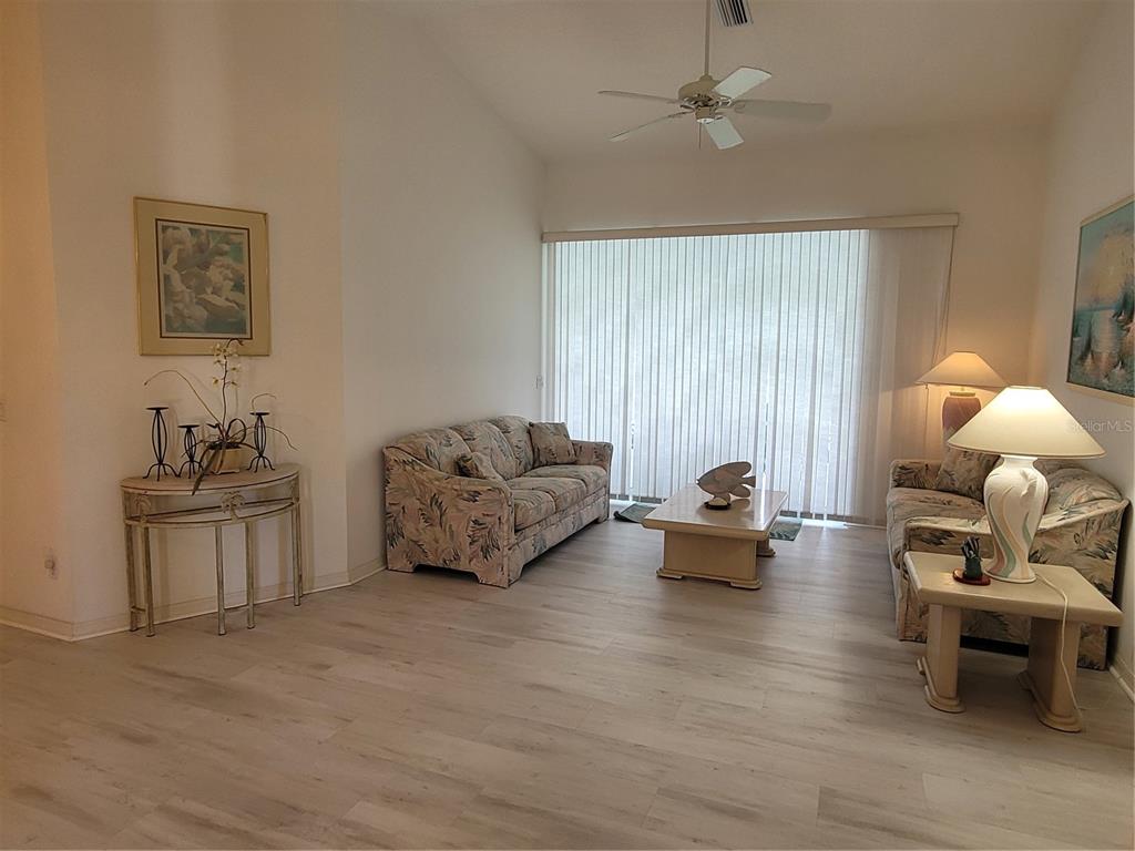A living room features light wood-look flooring, two floral sofas, and a large sliding glass door — 80 MARINER LANE, ROTONDA WEST, FL