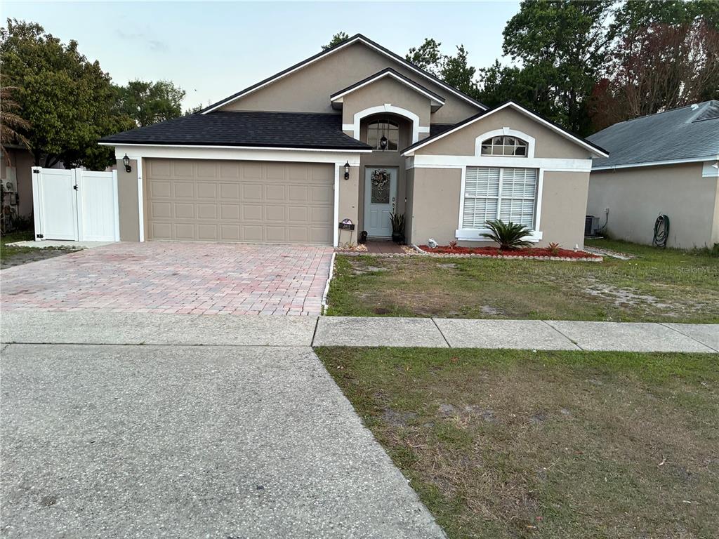 A single-story house with a beige stucco exterior, a two-car garage, and a paved driveway — 2431 TITUS COURT, ORLANDO, FL