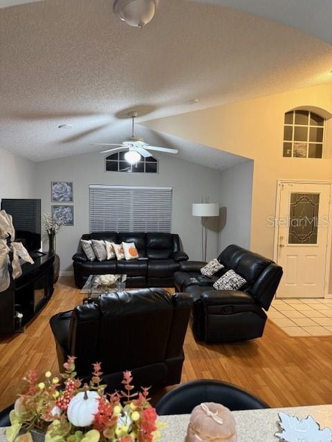 A living room features black leather furniture, wood flooring, and a vaulted ceiling with a fan — 2431 TITUS COURT, ORLANDO, FL