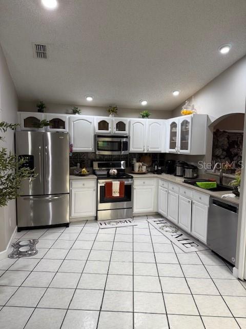 A kitchen features white cabinets, stainless steel appliances, and light-colored tile flooring — 2431 TITUS COURT, ORLANDO, FL