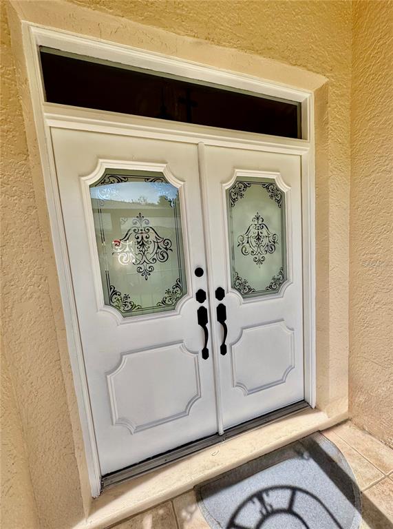 A white double front door with decorative glass panels and a transom window — 5688 LEGEND HILLS LANE, SPRING HILL, FL