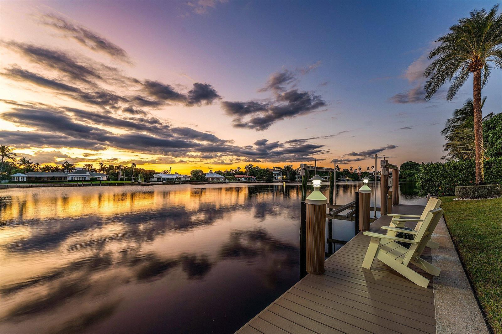 A wooden dock with two chairs overlooks a calm canal at sunset — 50 Spoonbill Road, Manalapan FL 33462, MANALAPAN, FL