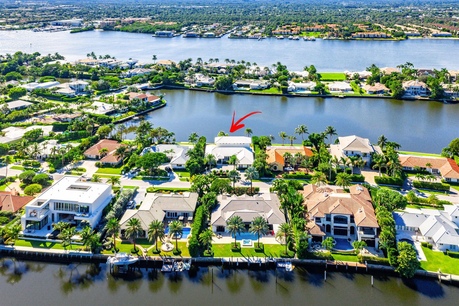 An aerial view shows a waterfront neighborhood with luxury homes, swimming pools, and boat docks — 50 Spoonbill Road, Manalapan FL 33462, MANALAPAN, FL