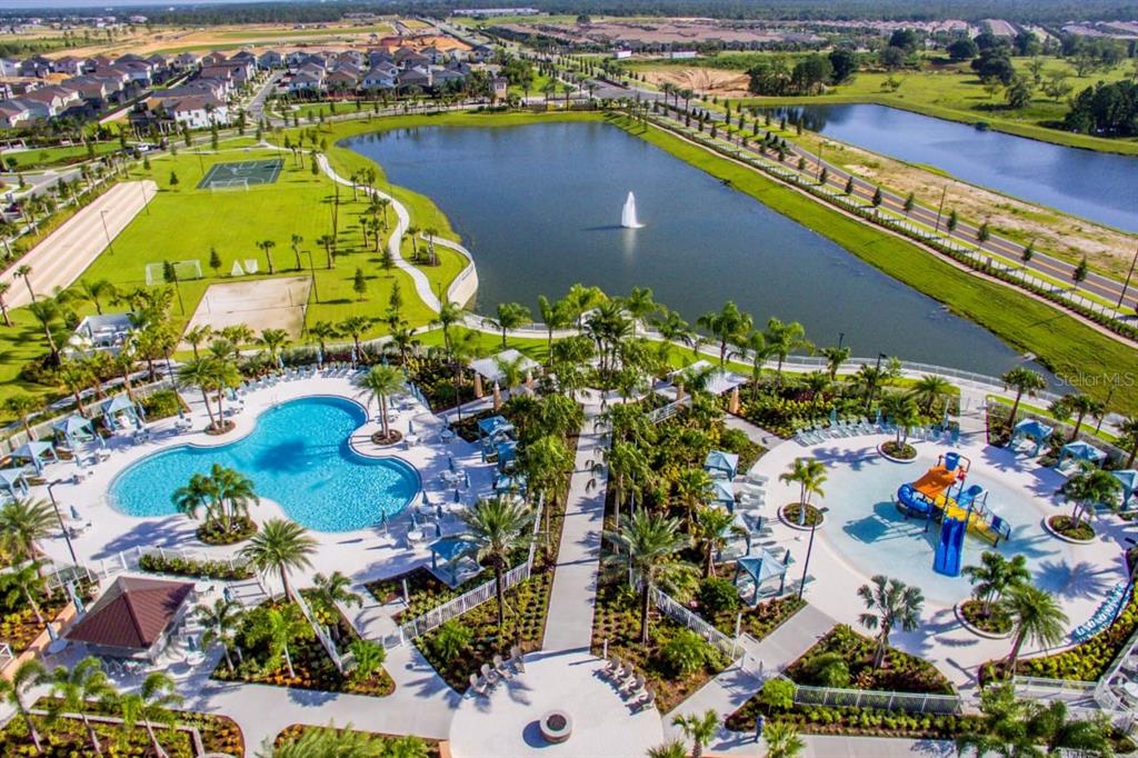 An aerial view of a community pool area with a pond, fountain, and sports courts — 1534 CAREY PALM CIRCLE, KISSIMMEE, FL