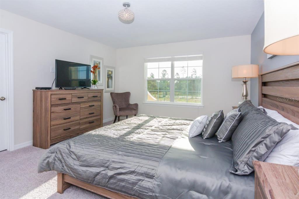 A bedroom features a wooden bed frame, a matching dresser, and a gray armchair — 1534 CAREY PALM CIRCLE, KISSIMMEE, FL