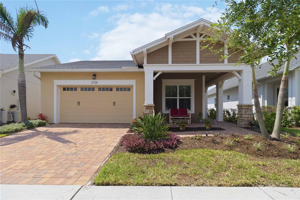 A single-story house with a tan garage, a covered front porch, and a paved driveway — 2724 SOUTHLAND STREET, ST CLOUD, FL