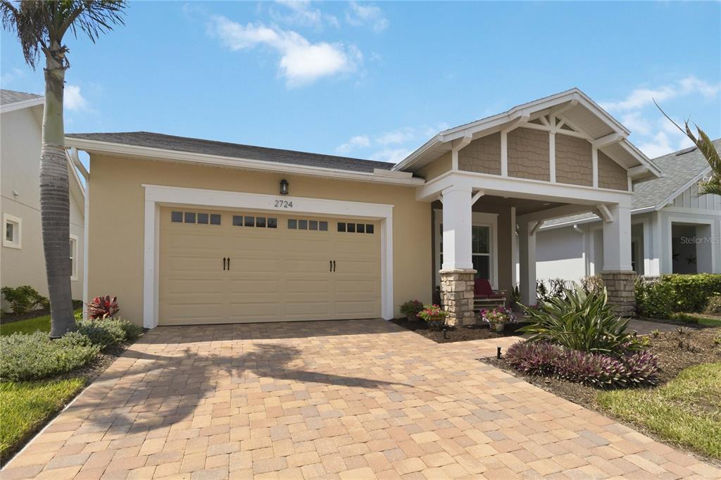 A tan single-story house with a stone-accented porch and a paved driveway — 2724 SOUTHLAND STREET, ST CLOUD, FL
