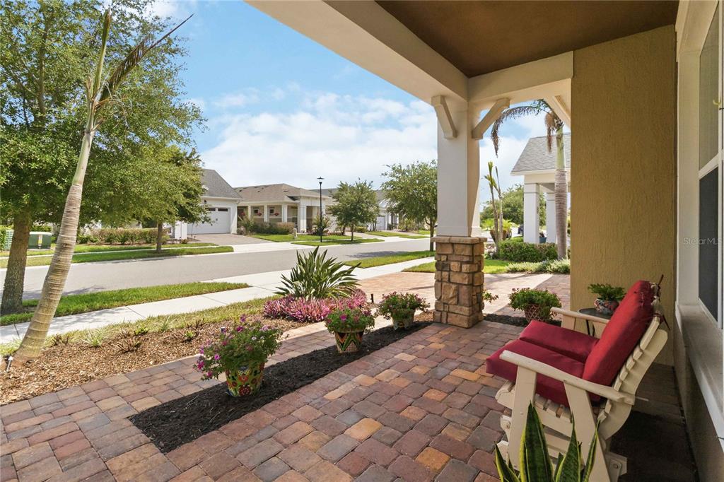 A covered front porch features brick pavers, a red loveseat, and potted plants — 2724 SOUTHLAND STREET, ST CLOUD, FL