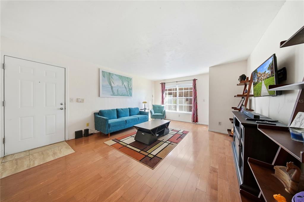 A living room features hardwood floors, a blue sofa, a coffee table, and a television — 10200 N GANDY BOULEVARD UNIT 714, ST PETERSBURG, FL