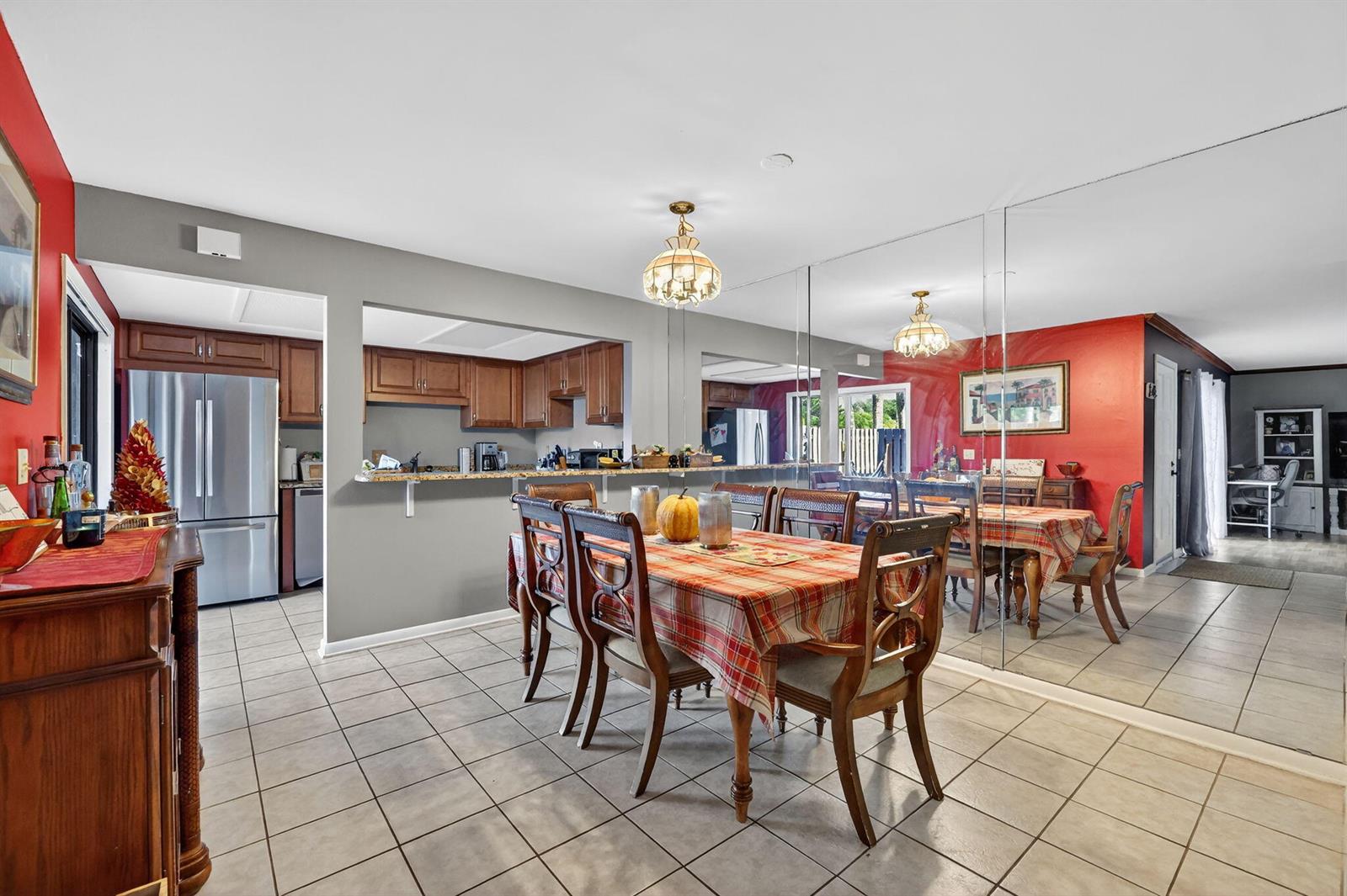 A dining room with a plaid tablecloth, tiled floors, and a large mirrored wall — 3860 Jefferson Street, Stuart FL 34997, STUART, FL