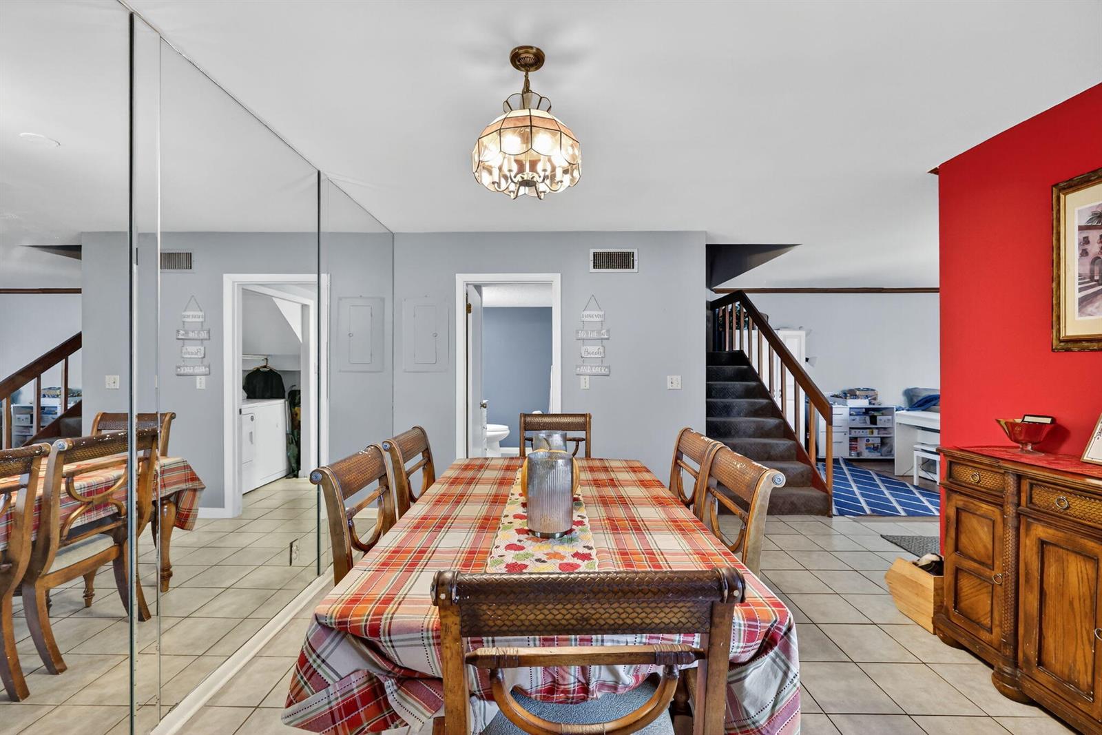A dining room features a plaid tablecloth, a mirrored wall, and stairs leading to another level — 3860 Jefferson Street, Stuart FL 34997, STUART, FL