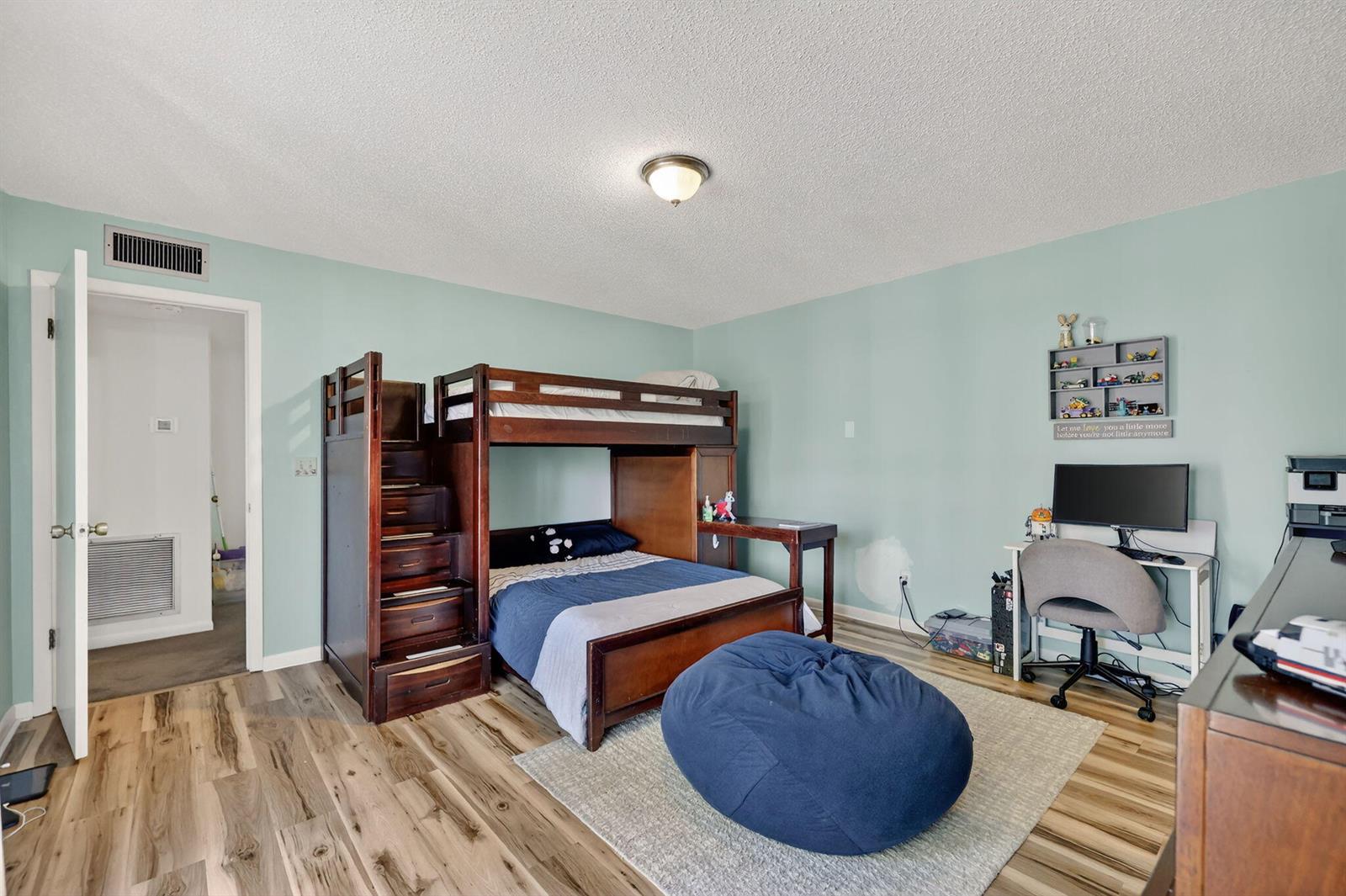 A bedroom with light blue walls, wood-look flooring, a bunk bed, and a desk area — 3860 Jefferson Street, Stuart FL 34997, STUART, FL