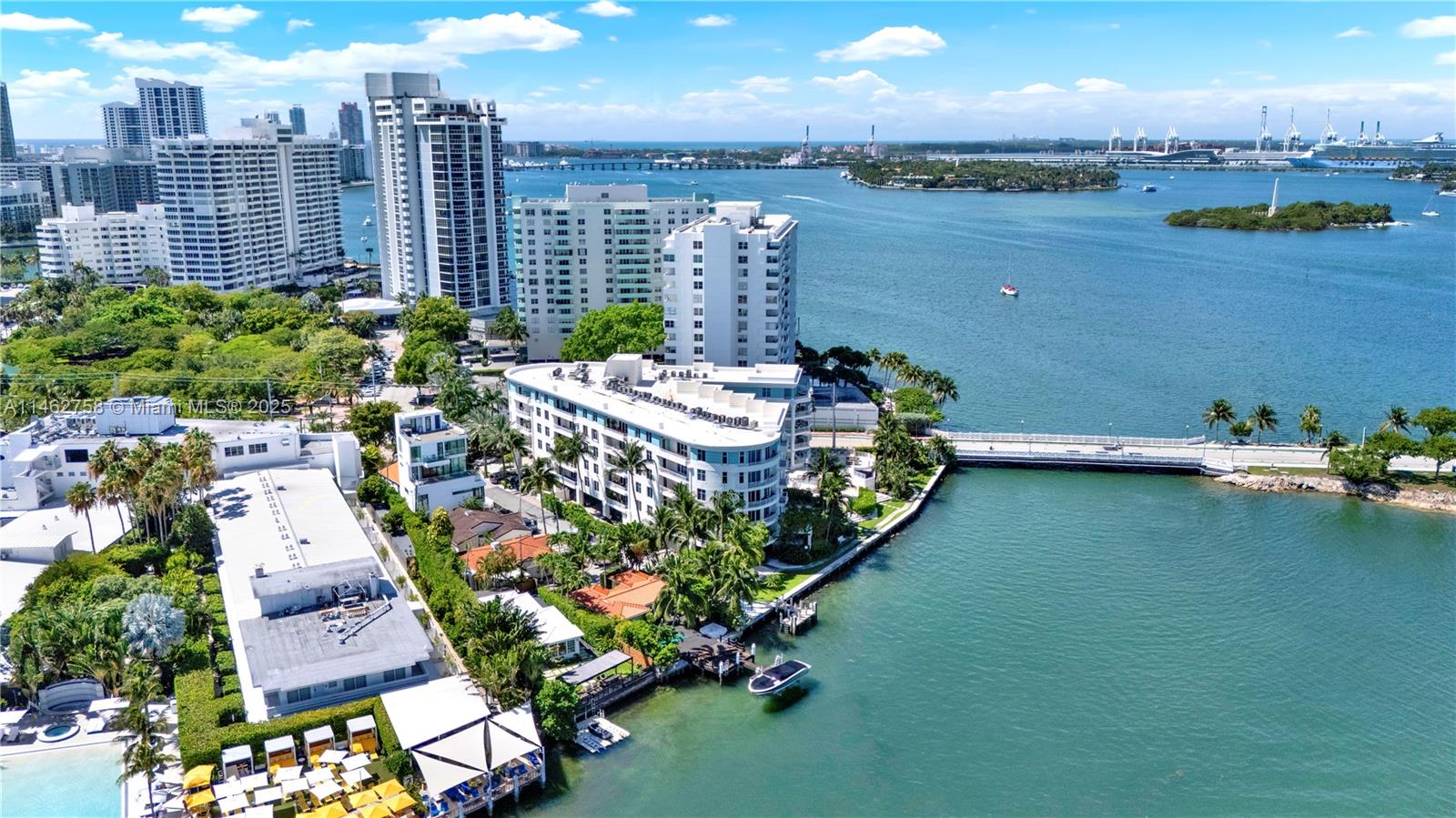 An aerial view shows waterfront residential buildings, a bridge, and a boat in Miami — 1 Century Ln # 209, Miami Beach FL 33139, MIAMI BEACH, FL