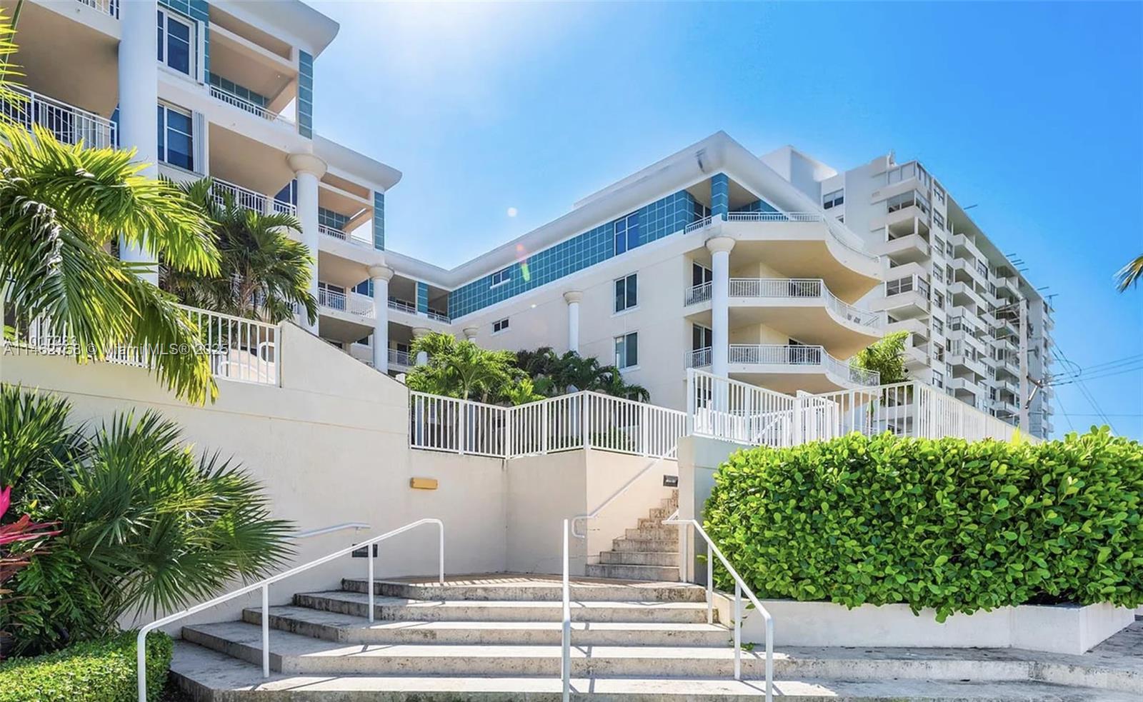 A wide outdoor staircase leads up to a multi-story apartment building with white balconies — 1 Century Ln # 209, Miami Beach FL 33139, MIAMI BEACH, FL