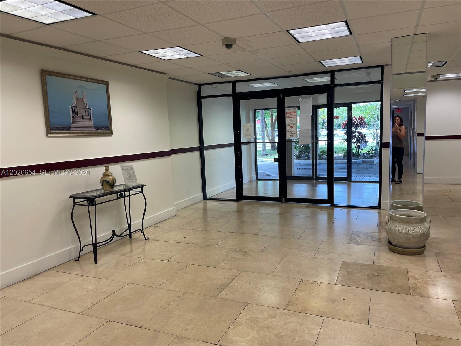A tiled lobby features a glass-paneled entrance, a console table, and a framed wall painting — 4174 Inverrary Dr # 903, Lauderhill FL 33319, LAUDERHILL, FL