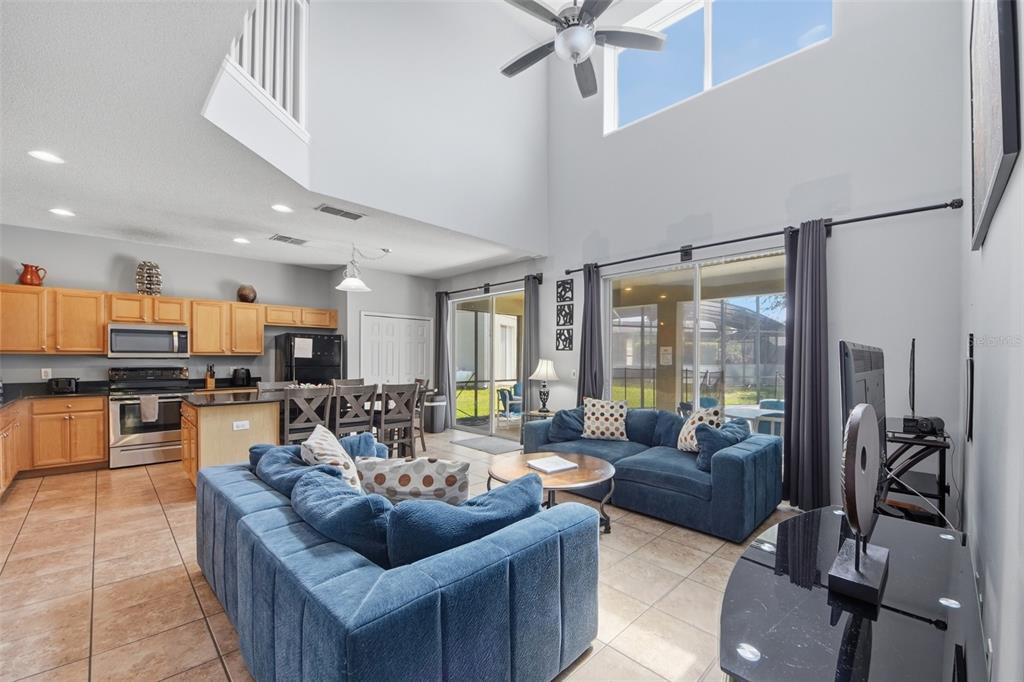 An open-concept living room and kitchen with high ceilings, tile floors, and blue sofas — 2708 LIDO KEY DRIVE, KISSIMMEE, FL