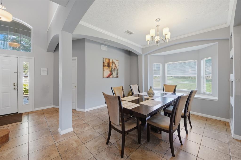 A dining room features a dark wood table, six chairs, tile flooring, and a chandelier — 2708 LIDO KEY DRIVE, KISSIMMEE, FL