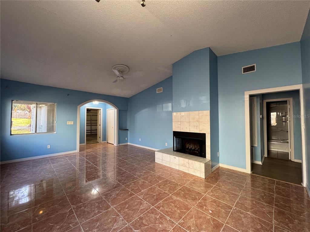 A living room features blue walls, a tiled fireplace, and brown marble-look floor tiles — 7237 HARBOR HEIGHTS CIRCLE, ORLANDO, FL