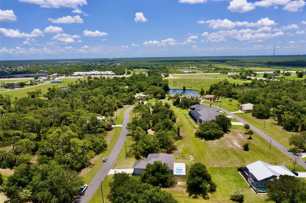 An aerial view shows houses situated on large, wooded lots near a small pond — 16760 ACAPULCO ROAD, PUNTA GORDA, FL