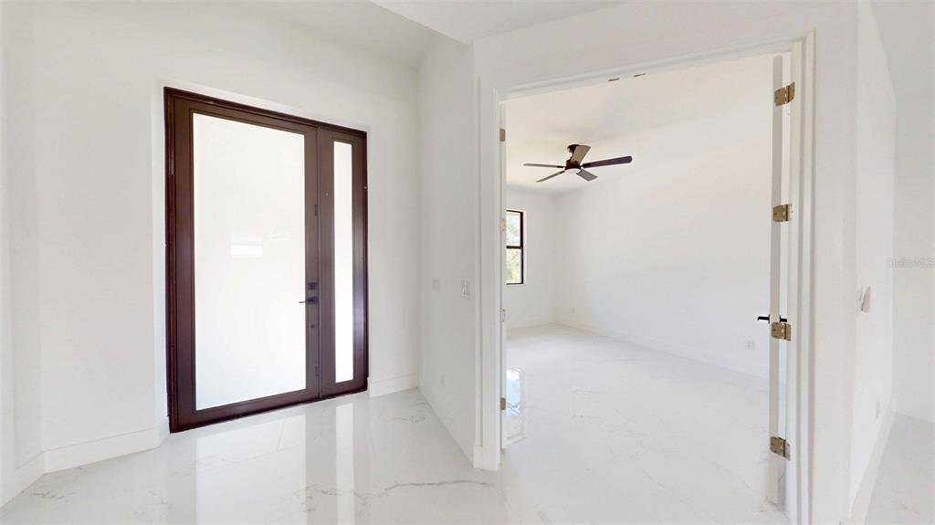 An entryway with a dark-framed glass door leads into a room with white tile floors — 16760 ACAPULCO ROAD, PUNTA GORDA, FL