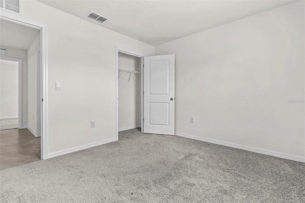 An empty bedroom features grey carpet, white walls, a closet, and an open doorway — 10306 SE 161ST LANE ROAD, SUMMERFIELD, FL
