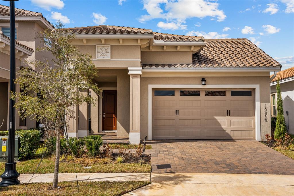 A single-story house with a tan stucco exterior, tile roof, and a two-car garage — 13315 CAMBORNE PLACE, ORLANDO, FL