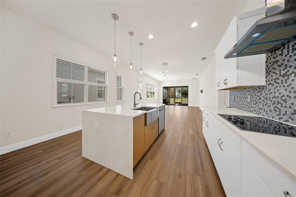 A modern kitchen features a white quartz island, wood cabinets, and a gray honeycomb backsplash — 13315 CAMBORNE PLACE, ORLANDO, FL