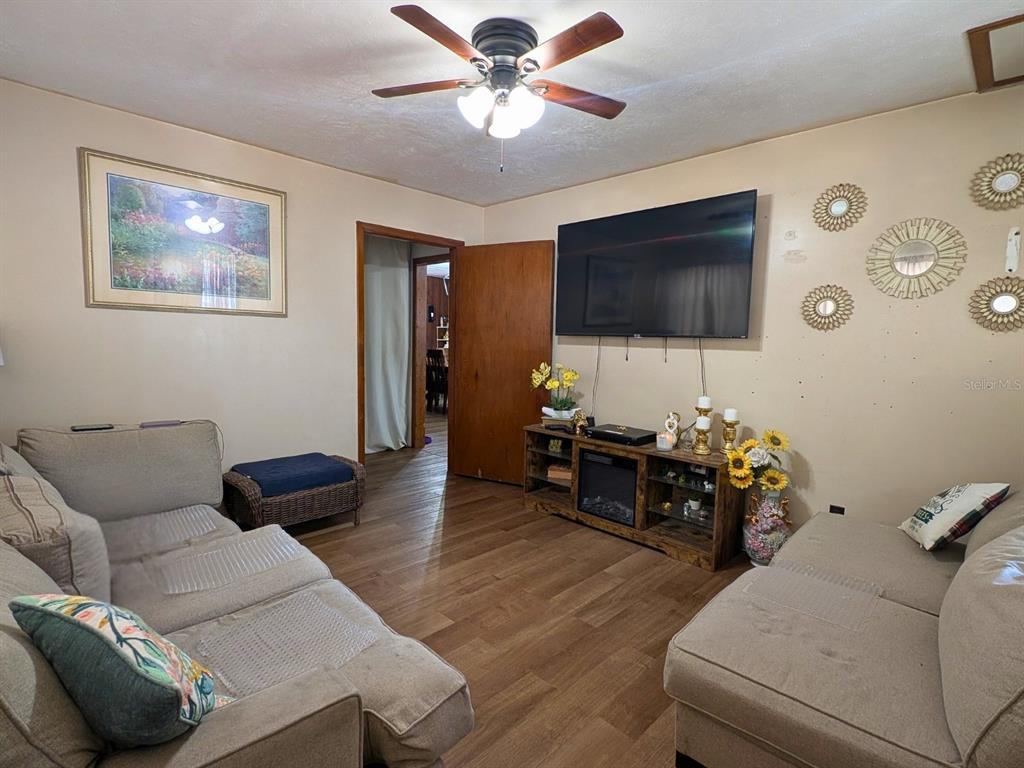A living room features two sofas, a wall-mounted television, and a wood-finish media console — 7101 JEANNE AVENUE, HUDSON, FL