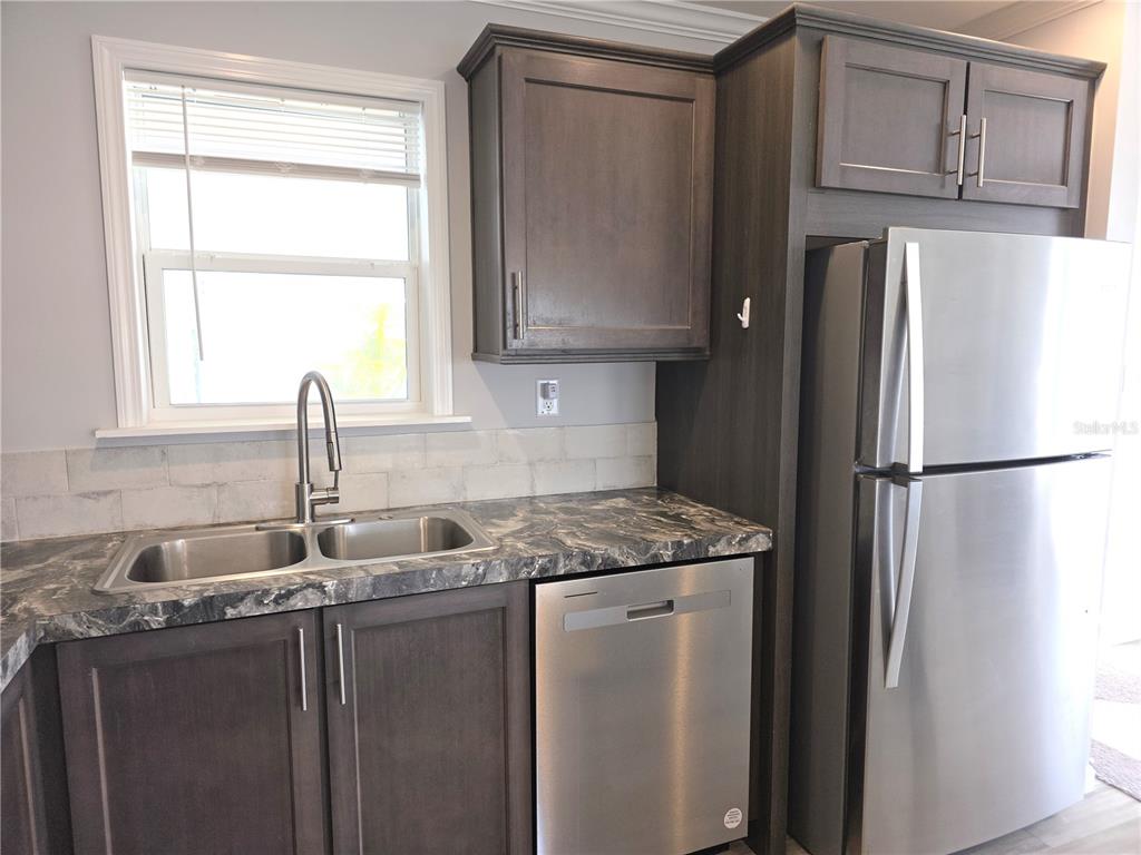 A kitchen features dark wood cabinets, stainless steel appliances, a double sink, and marble-patterned countertops — 236 WOLVERINE AVENUE, NORTH PORT, FL