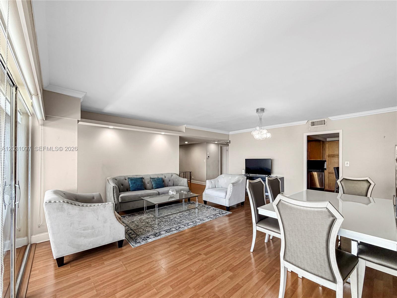 A living and dining area features hardwood floors, a grey sofa, and neutral walls — 1800 NE 114th St # 1607, Miami FL 33181, MIAMI, FL