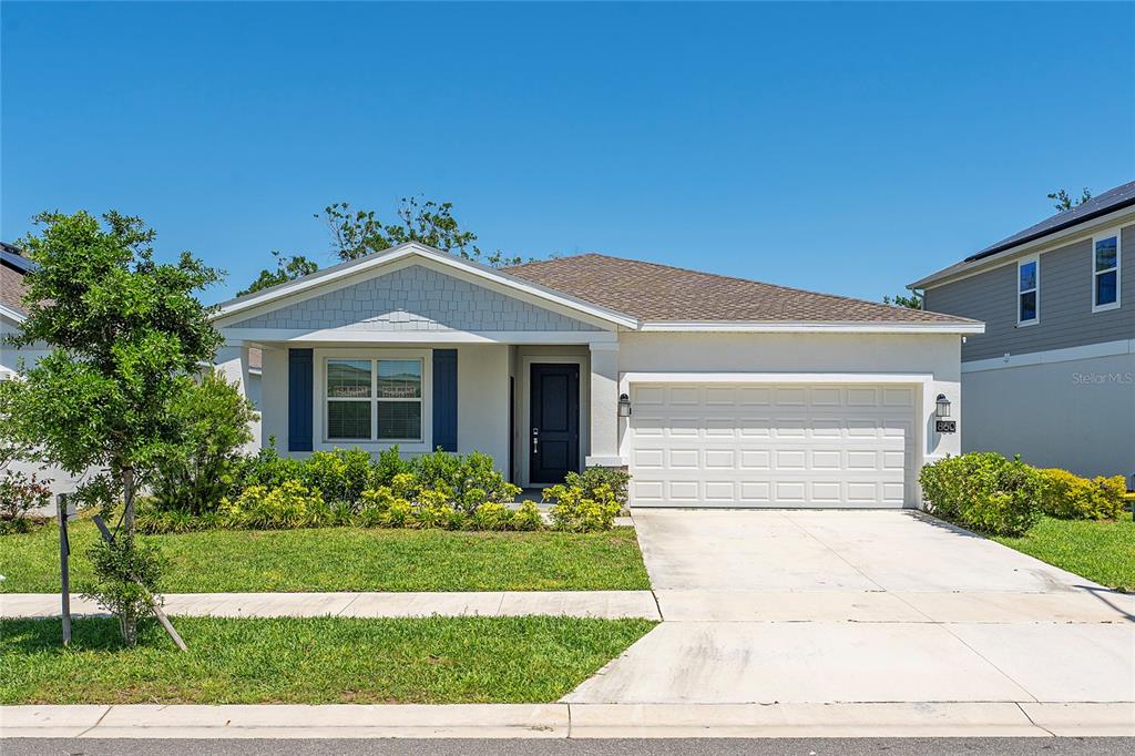 A single-story house with a white garage, blue shutters, and a front lawn — 860 DARING DRIVE, DAVENPORT, FL