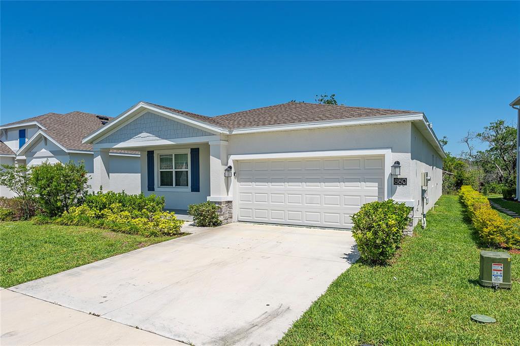 A single-story house with a white stucco exterior, a two-car garage, and a front lawn — 860 DARING DRIVE, DAVENPORT, FL